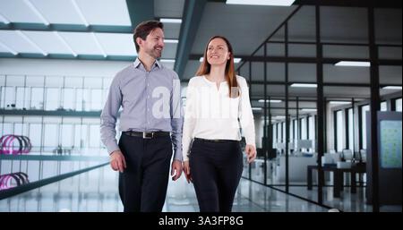 Colleagues walking together, smiling, having a happy workplace conversation. Stock Photo