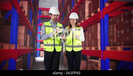 New warehouse employee receiving training from experienced manager using tablet. Stock Photo