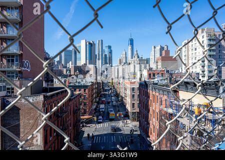 The skyline of lower Manhattan in New York City seen through a hole in a wire mesh fence Stock Photo