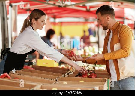 Taking apples. Man is buying products on the street market or bazaar from woman. Stock Photo