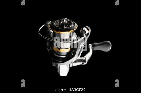 Fishing reel isolated on black background. Tackle. Fishing spinning reel. Stock Photo