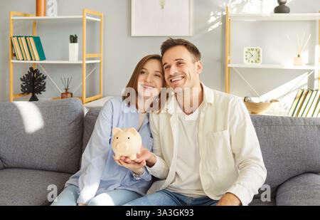 Happy Couple Holding Piggy Bank Saving Money At Home Stock Photo
