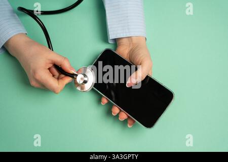A woman listens to a telephone with a stethoscope. Diagnostics and repair. Identifying technical issues, diagnosing device malfunctions. Troubleshooti Stock Photo