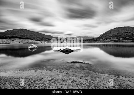 Flooded house reflected in the Villajoyosa reservoir with moving clouds in the background. Stock Photo