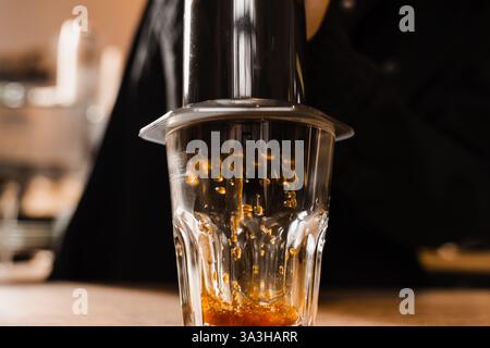Falling coffee drops in cup close-up. Aeropress coffee. Process of pouring coffee in cup. Barista is pushing aeropress for pouring coffee drops Stock Photo