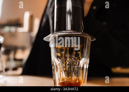 Aeropress coffee. Process of pouring coffee in cup. Barista is pushing aeropress for pouring coffee drops. Falling coffee drops in cup close-up Stock Photo