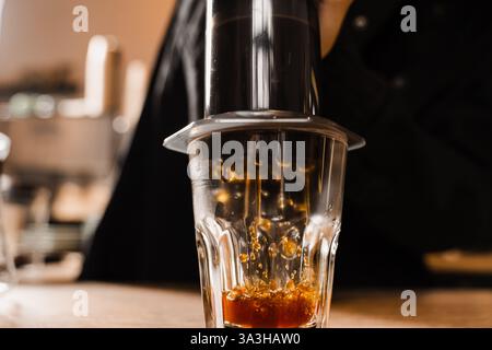 Aeropress coffee. Process of pouring coffee in cup. Barista is pushing aeropress for pouring coffee drops. Falling coffee drops in cup close-up Stock Photo