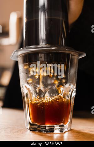 Aeropress coffee. Process of pouring coffee in cup. Barista is pushing aeropress for pouring coffee drops. Falling coffee drops in cup close-up Stock Photo