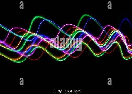 A long exposure photograph of colourful lights in swirl patterns of motion against a black background Stock Photo
