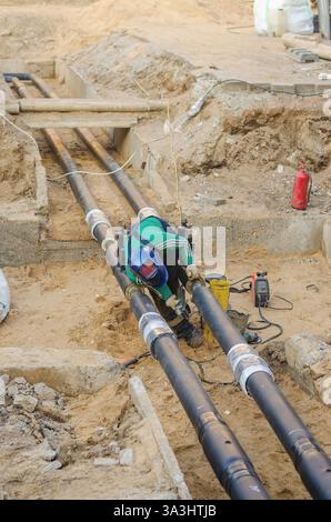 Welder working on underground pipeline installation at a construction site. High quality photo Stock Photo