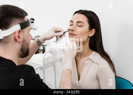 Consultation with ENT doctor. Otolaryngologist examines girl nose before procedure of endoscopy of nose. Rhinoscopy of woman nose Stock Photo