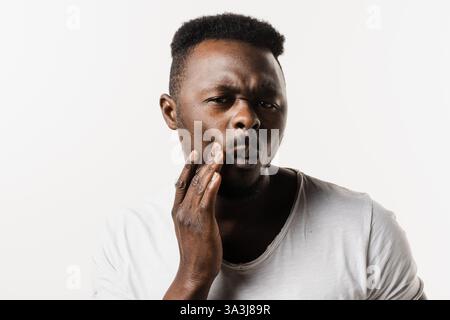 African american man is touching cheek and feeling toothache pain and discomfort of tooth. African man with tooth decay, infection or injury to the to Stock Photo