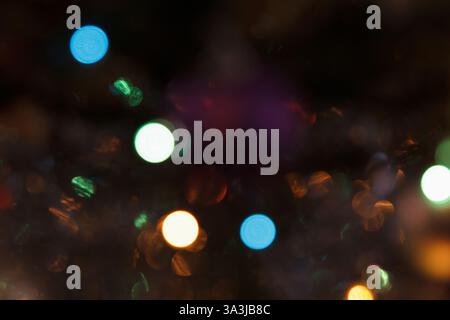 Blurry multicolored lights in soft focus on a dark background. Abstract bokeh effect creating a festive and dreamy atmosphere Stock Photo