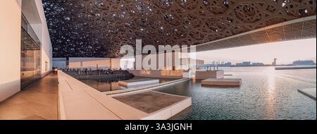 17 January 2025, Louvre museum Abu Dhabi, UAE: Museum dome reflecting sunset light in the water at dusk Stock Photo