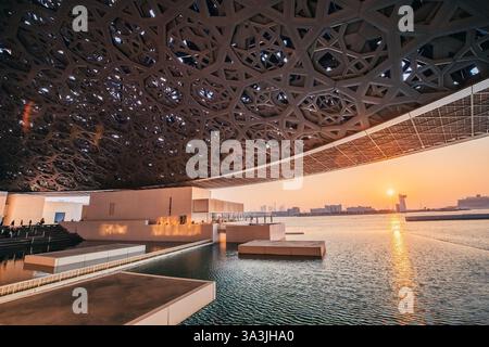 17 January 2025, Louvre museum Abu Dhabi, UAE: Museum dome reflecting sunset light in the water at dusk Stock Photo
