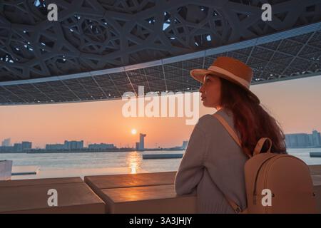 17 January 2025, Louvre museum Abu Dhabi, UAE: Young tourist woman admiring sunset at the Louvre Museum Stock Photo