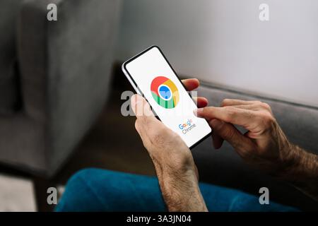 Man using a mobile phone with the Google Chrome browser on the screen. Rosario, Argentina - March 15, 2025. Stock Photo