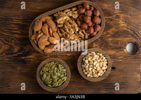 Assortment of nuts in bowls on wooden background. Top view Stock Photo