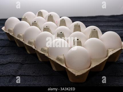 A carton filled with white eggs rests on a dark textured surface, showcasing fresh ingredients ideal for various recipes or baking projects in the kit Stock Photo