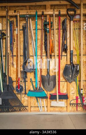 Neatly arranged and stored assorted gardening tools on wall inside garden shed. Stock Photo