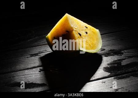 sliced yellow watermelon on black wood background Stock Photo