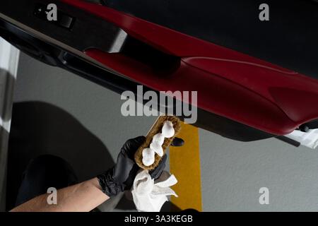 Process of removing dust and dirt from the auto door panel. Car detailer cleans the auto door with brush and detergent Stock Photo