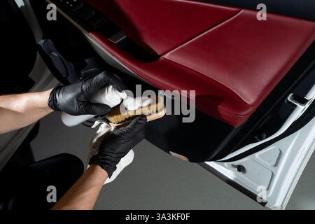 Process of removing dust and dirt from the auto door panel. Car detailer cleans the auto door with brush and detergent Stock Photo