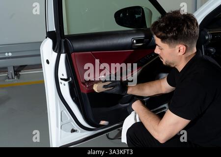 Process of removing dust and dirt from the auto door panel. Car detailer cleans the car door with brush and detergent Stock Photo