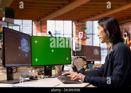 Senior developer using mockup PC in artificial intelligence focused startup, debugging applications. Experienced IT expert doing code testing and quality assurance on green screen computer Stock Photo