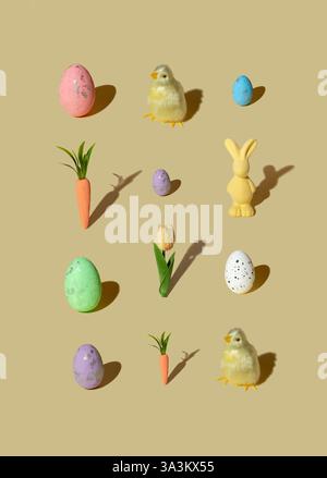 Pattern made of colored eggs, flower, carrot, bunny, chicken on pastel beige background. Minimal Easter concept. Stock Photo
