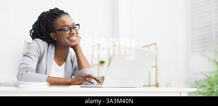 African American Woman Looking At Laptop Screen In Office Stock Photo