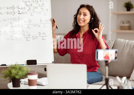 Young middle eastern woman teaching mathematics online in a modern living room Stock Photo