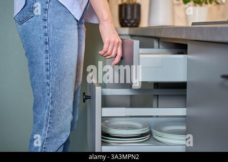 Person opens a kitchen drawer with various utensils in wooden cutlery tray. Woman opening kitchen cabinet. Concept of home organization and functional Stock Photo