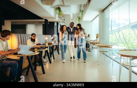 A diverse group of college friends walking together in a university campus hallway, highlighting friendship and the vibrant atmosphere of student life Stock Photo
