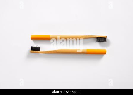 Bamboo toothbrushes with black bristles promoting oral hygiene and eco-friendly lifestyle on a minimalist white backdrop Stock Photo