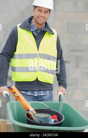 cheerful labourer pushing a clean wheelbarrow Stock Photo