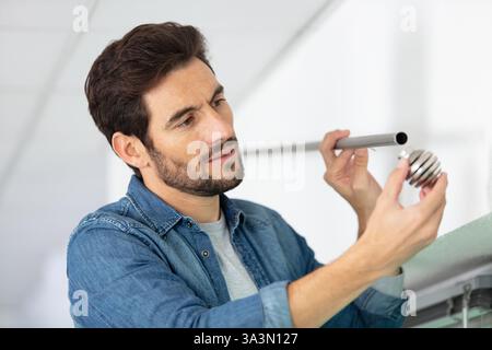 worker installing window curtain rod on the wall Stock Photo