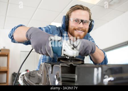 man using angle grinder in workshop Stock Photo