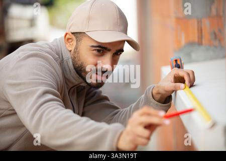 male builder measuring window sill Stock Photo