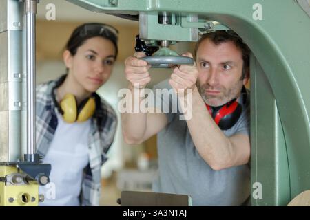 man working with female apprentice in factory Stock Photo