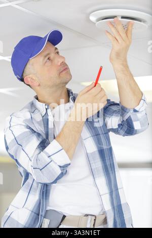 male technician installing ceiling fan Stock Photo