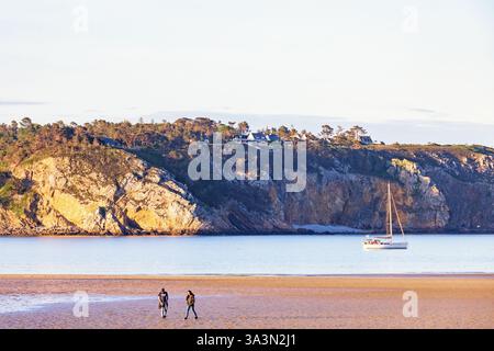 Man and woman walking on a beach by the sea in the evening Stock Photo