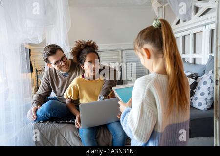 Excited single father plays with diverse, multi-ethnic daughters. Using digital tablet enjoy weekend Stock Photo
