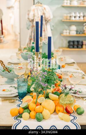 Citrus-inspired tablescape with vibrant fruits and blue candles. Stock Photo