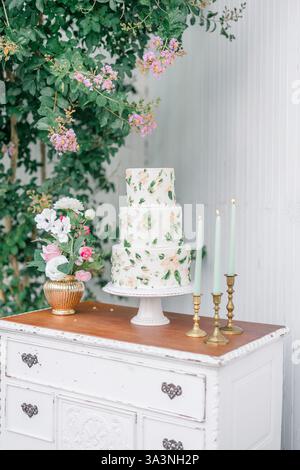Floral wedding cake on a vintage table with pink flowers and candles. Stock Photo