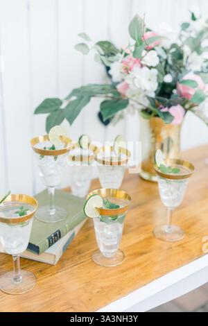 Refreshing lime cocktails in gold-rimmed glasses with floral decor Stock Photo