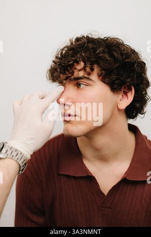 Rhinoplasty surgery preparation for man. ENT is touching nose and
