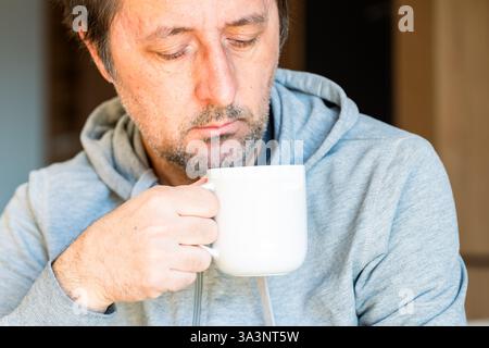 Relaxed causal man drinking coffee at home in the morning, selective focus Stock Photo