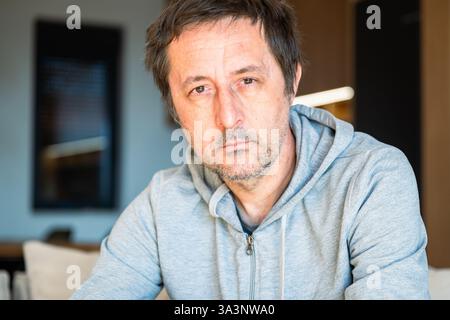 Portrait of serious casual mature adult male at home looking at camera, selective focus Stock Photo