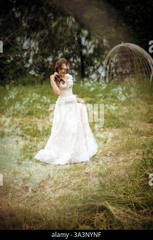 Stunning bride gracefully poses in a spring park, among blossoming trees. exuding elegance, Stock Photo